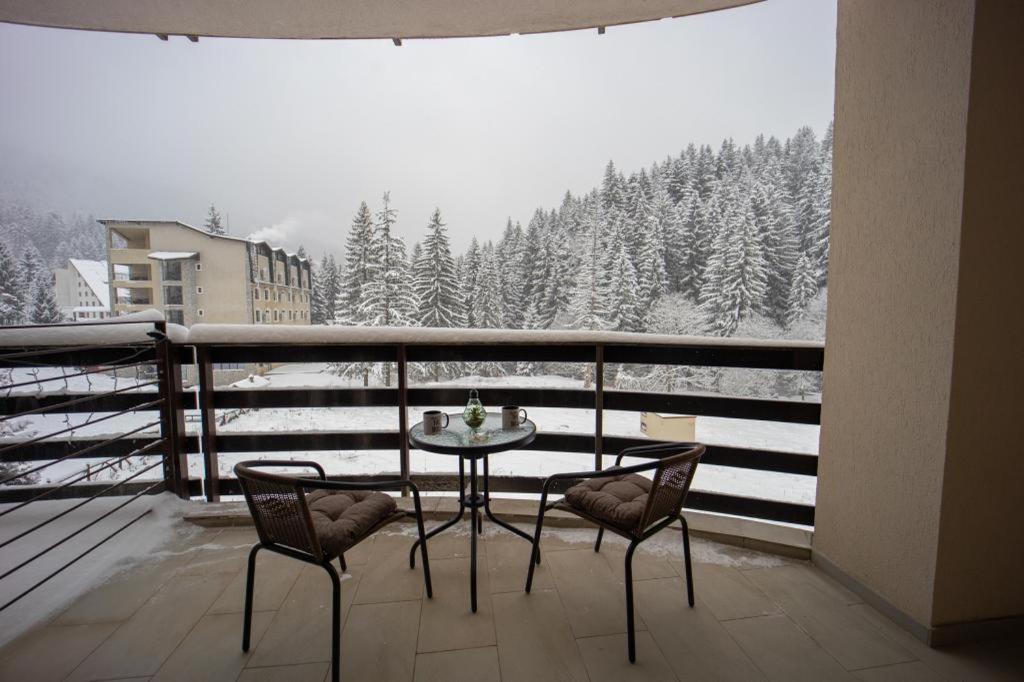 a table and chairs on a balcony with a snow covered forest at Postavaru Studio in Poiana Brasov