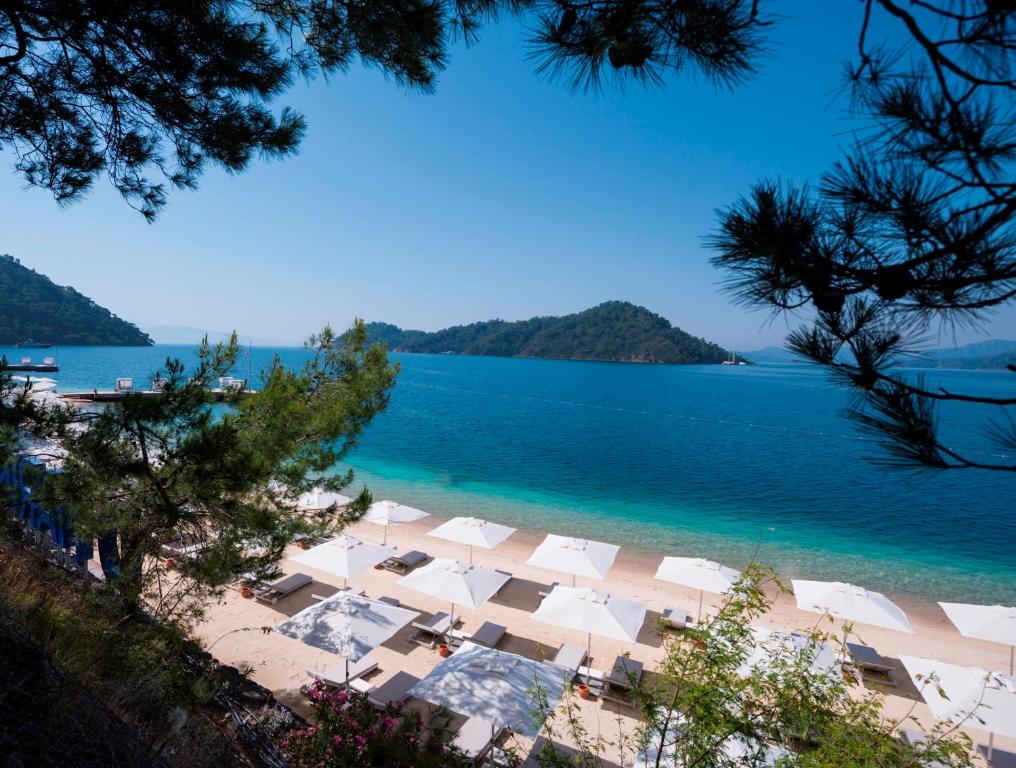 een uitzicht op een strand met witte parasols en het water bij D Resort Gocek Special Category in Göcek