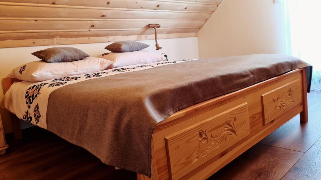 a wooden bed with two pillows on top of it at Apartament w Jałowcach in Gronków