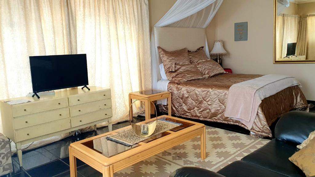 a bedroom with a bed and a tv and a table at Mosaic Guesthouse Welkom in Welkom