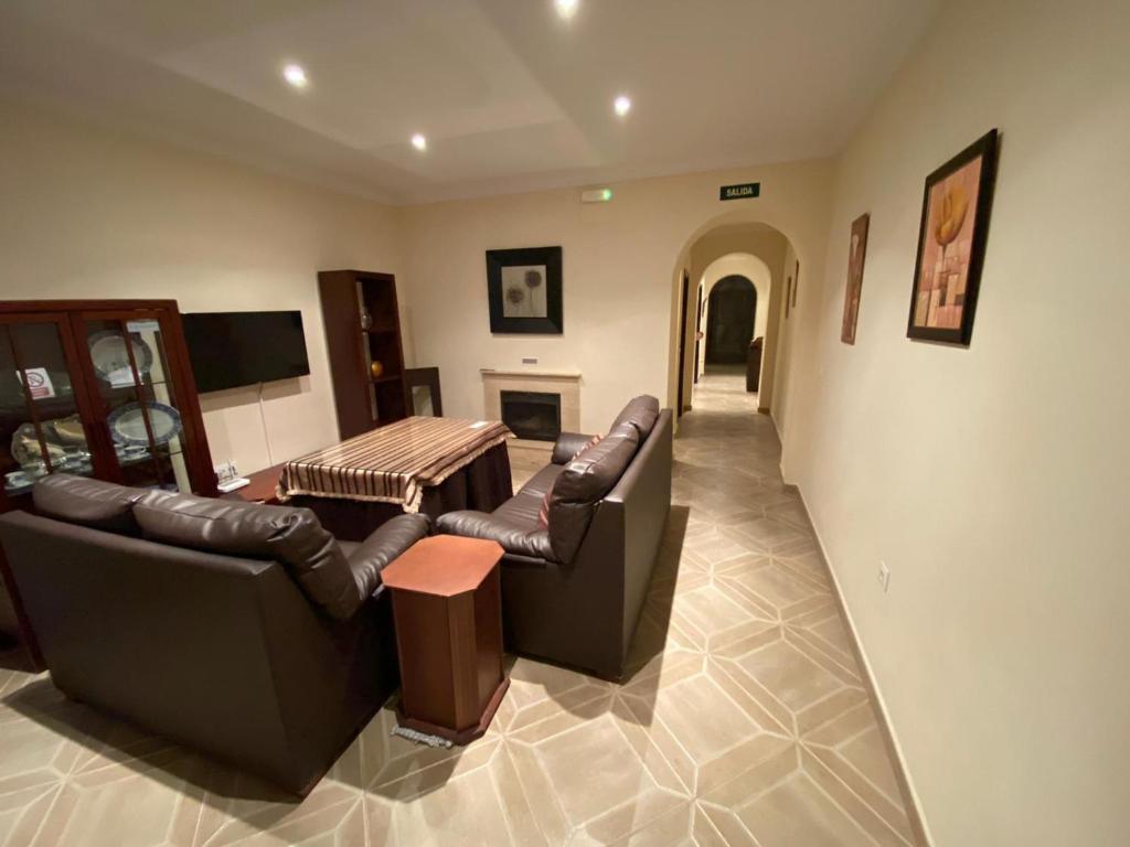 CASA BODONAL CENTRO R&S في Bodonal de la Sierra: غرفة معيشة مع كنبتين جلديتين وطاولة