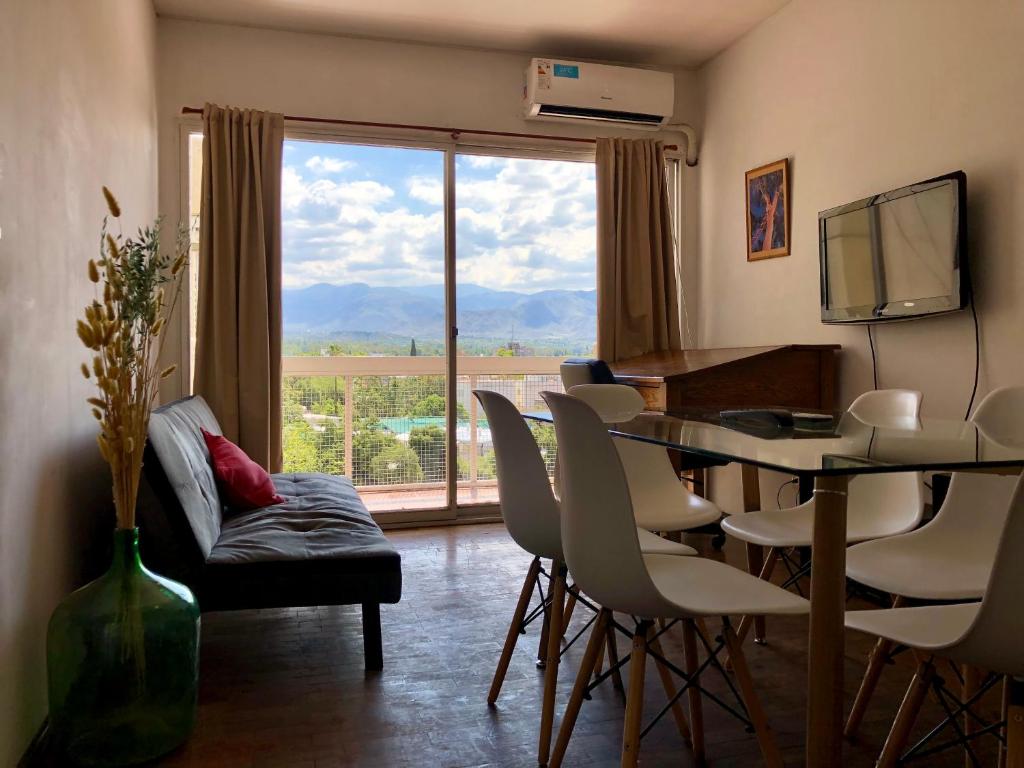 sala de estar con mesa, sillas y ventana grande en Apartamento Lela en Mendoza