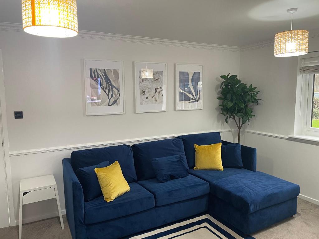 a blue couch in a living room with yellow pillows at Modern 1 Bed ground floor apartment in Dartford