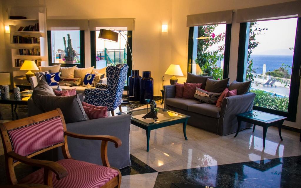 a living room with couches and chairs and the ocean at Kalidon Panorama Hotel in Kokkari