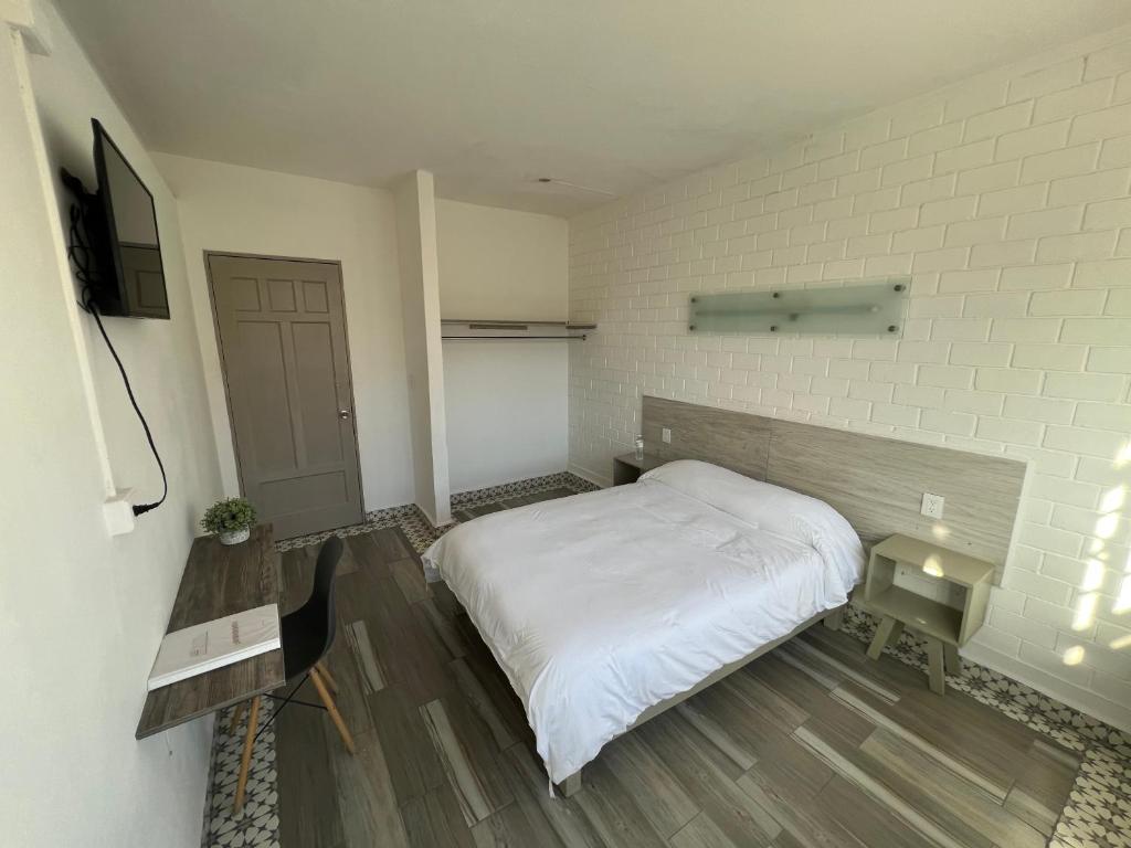 a bedroom with a white bed and a television at Hotel Insurgentes in San Luis Potosí