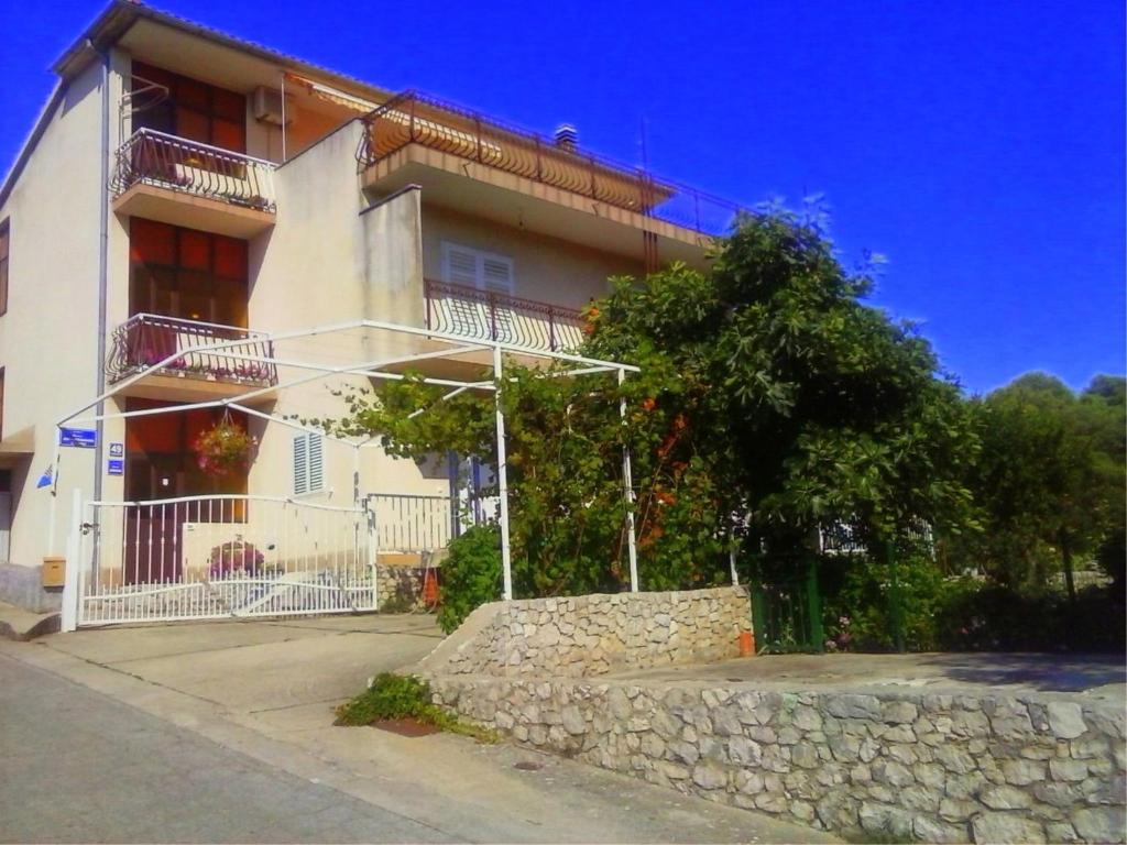 a white building with a stone wall in front of it at Siesta Apartments in Šibenik