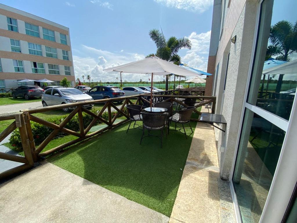patio con tavolo, sedie e ombrellone di Flat Terreo Muro Alto Condomínio Clube com Sala Reversível para segundo quarto a Porto De Galinhas