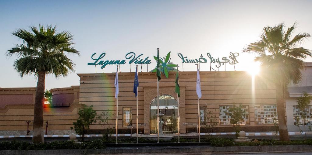 a building with a sign on top of it with palm trees at فندق لاجونا ڤيستا بريدة in Buraydah