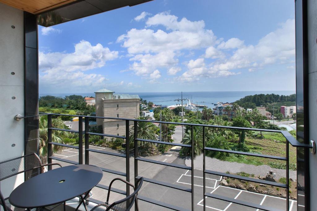 a balcony with a table and chairs and a view of the ocean at Familia Hotel in Seogwipo