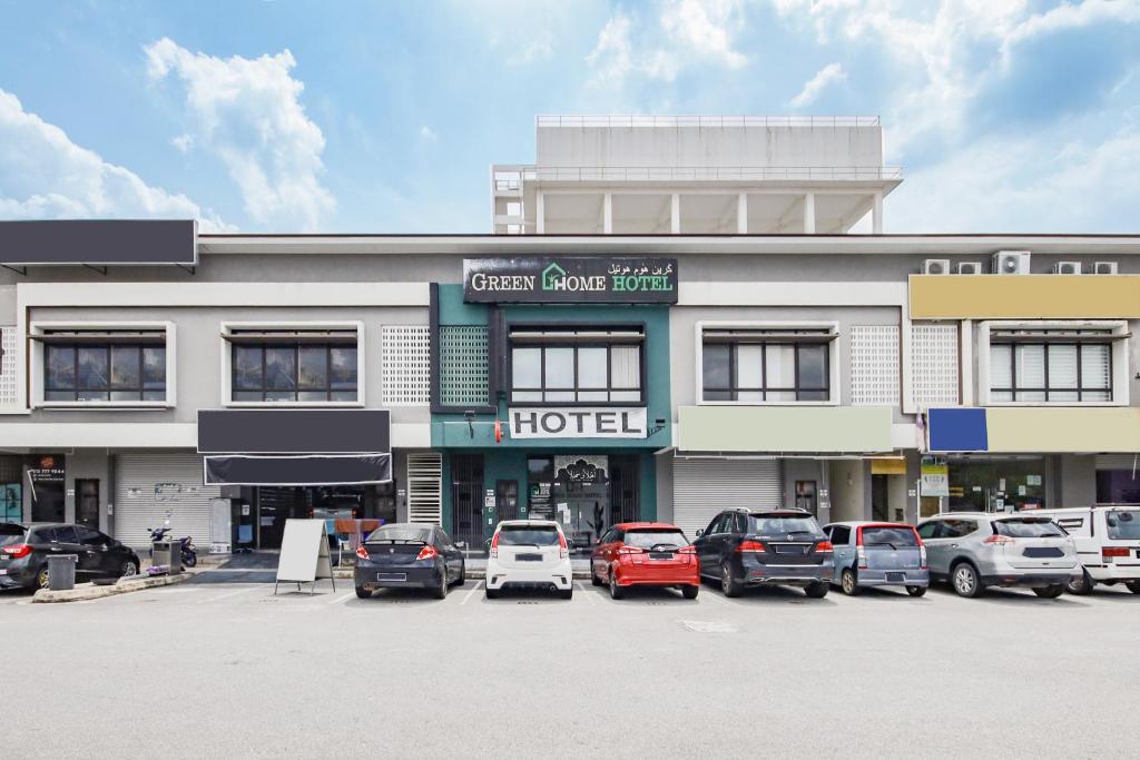 OYO 90399 Green Home Hotel syariah في سيبانغ: فندق فيه سيارات تقف امامه
