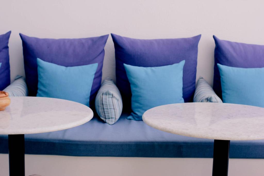 a couch with blue pillows and two tables at Kalidon Panorama Hotel in Kokkari