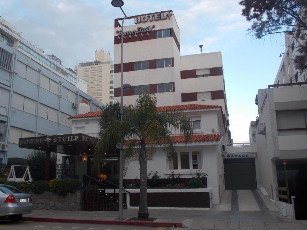 a hotel with a palm tree in front of a building at Bonne Etoile in Punta del Este