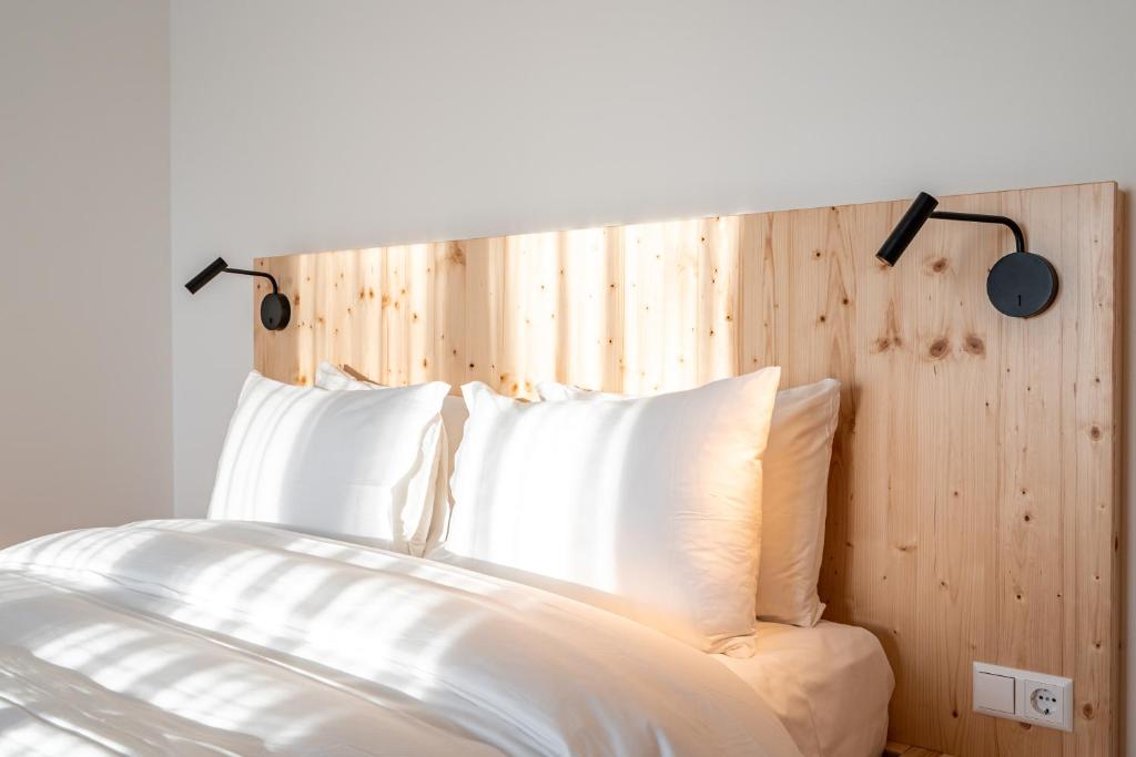 uma cama com almofadas brancas e uma cabeceira em madeira em Arbio Hotel Freiburg em Friburgo em Brisgóvia