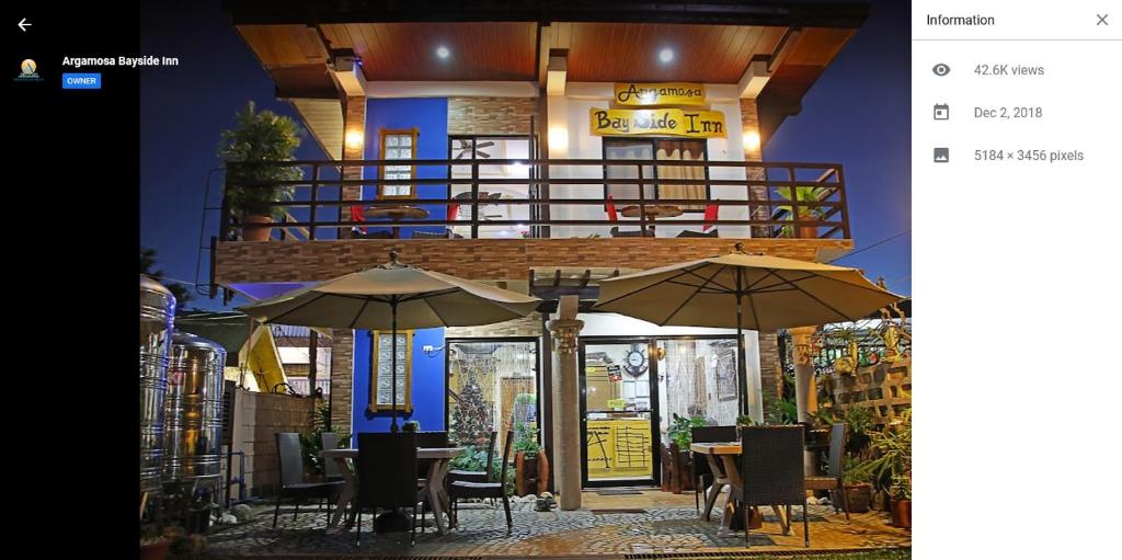een restaurant met tafels en parasols voor een gebouw bij Argamosa Bayside Inn in Coron