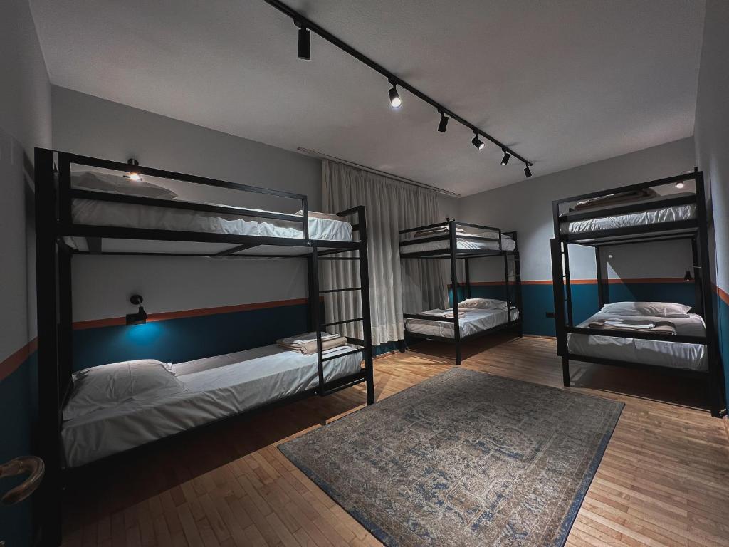 a bedroom with three bunk beds and a rug at The Bearded Dad Hostel in Tirana