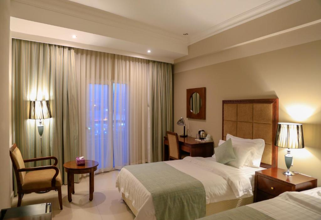 a hotel room with two beds and a desk and a bed at Muscat Inn Hotel in Muscat