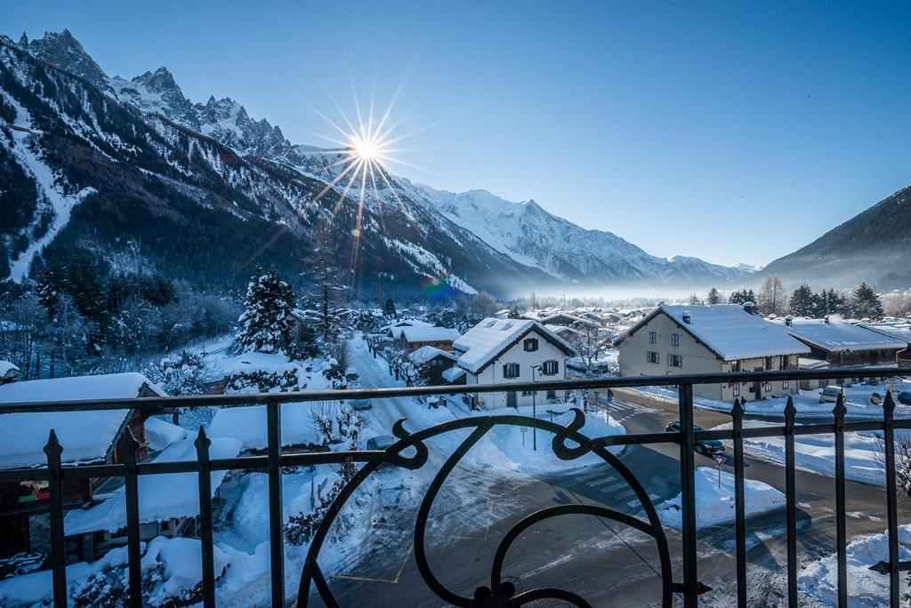 a view of a snowy mountain village with the sun shining at Eden Hotel, Apartments and Chalet Chamonix Les Praz in Chamonix