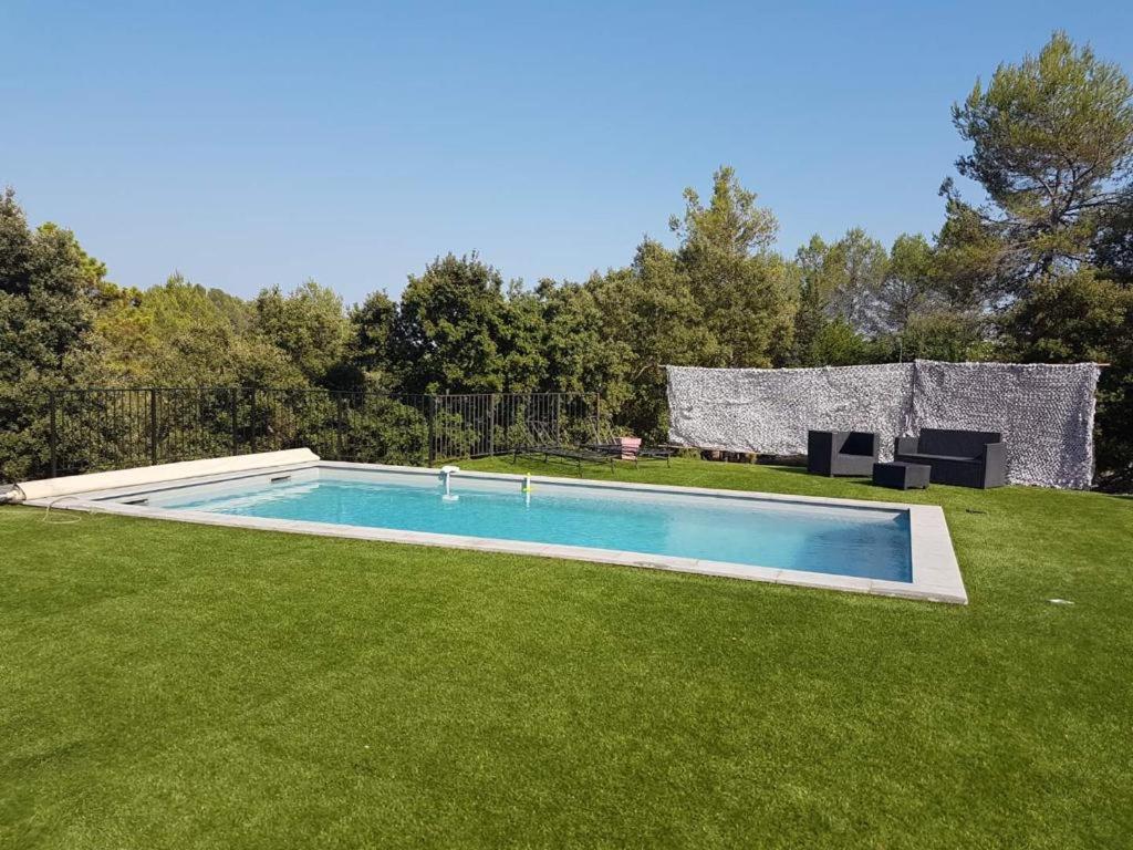 a swimming pool in a yard with green grass at Villa Coco avec jardin piscine et terrain de boules de 180 m carrés in Les Arcs sur Argens