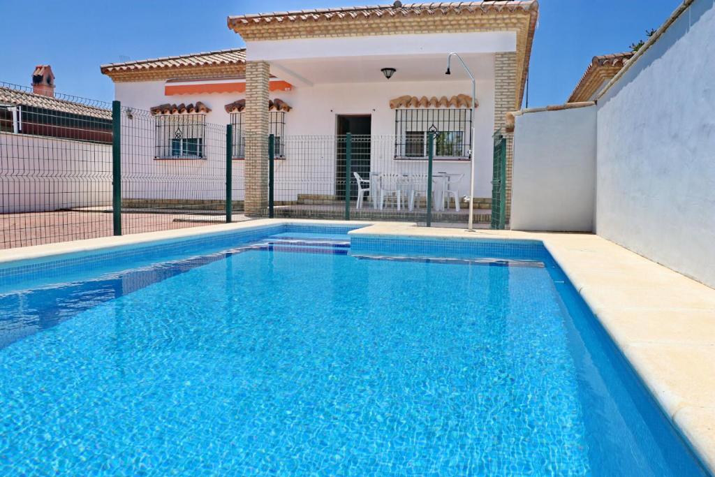 a swimming pool in front of a house at Chalet Pinar de Roche in Conil de la Frontera