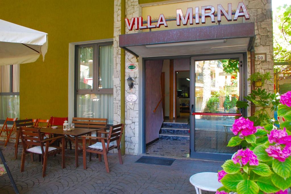 restauracja ze stołem i krzesłami przed budynkiem w obiekcie Villa Mirna w Rimini
