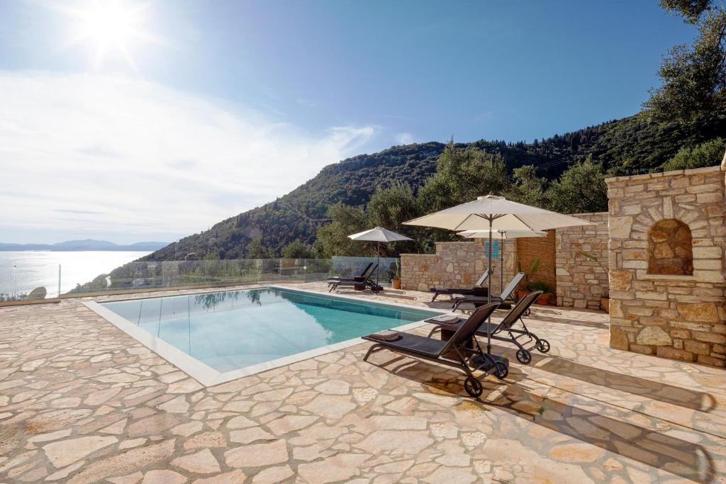 a swimming pool with two chairs and an umbrella at Villa Aphrodite in Agní