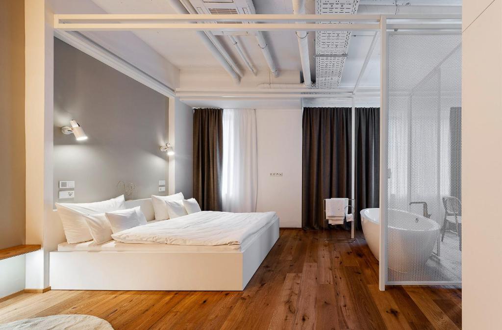 a bedroom with a white bed and a bath tub at QUI-Balingen in Balingen