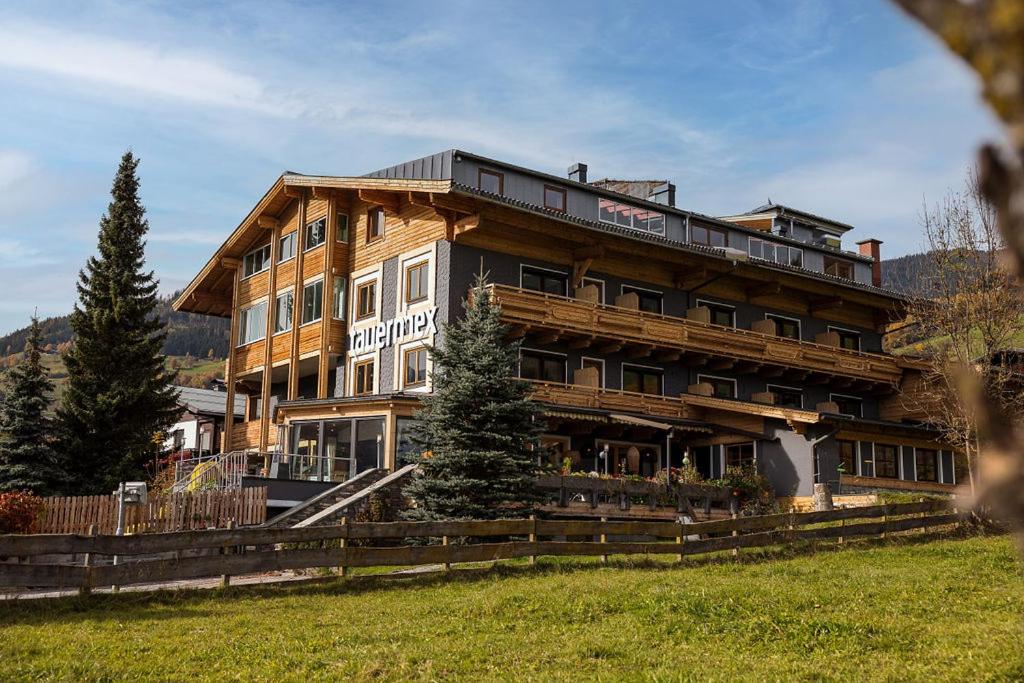 a large wooden building on a grassy field at Hotel . Wirtshaus TauernHex in Piesendorf