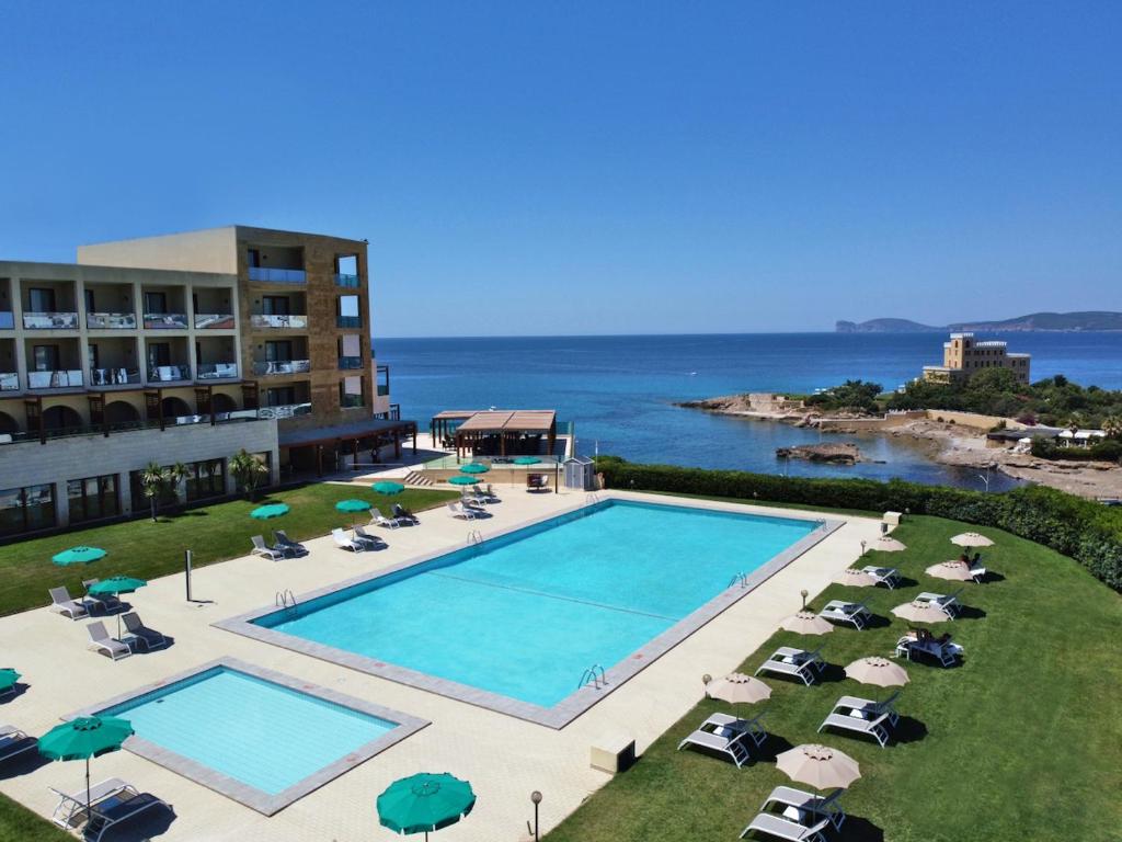 una vista sul soffitto di una piscina con sedie e ombrelloni di Smy Carlos V Wellness & Spa Alghero ad Alghero