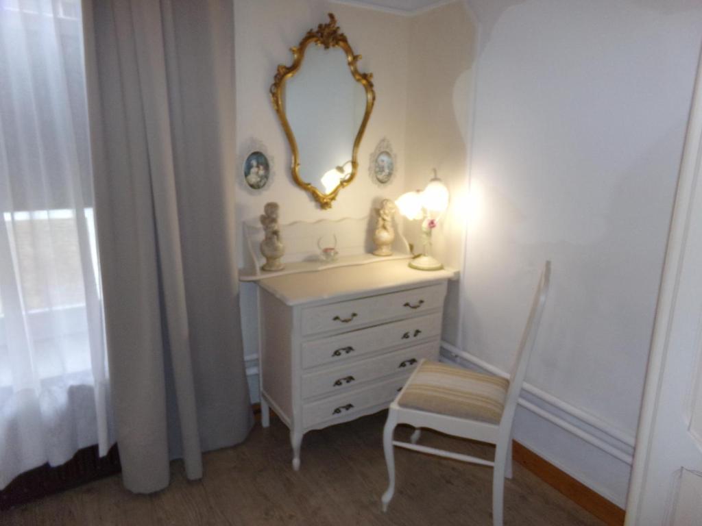 uma cómoda branca com um espelho e uma cadeira em Chez Len & Filipp em Bouillon