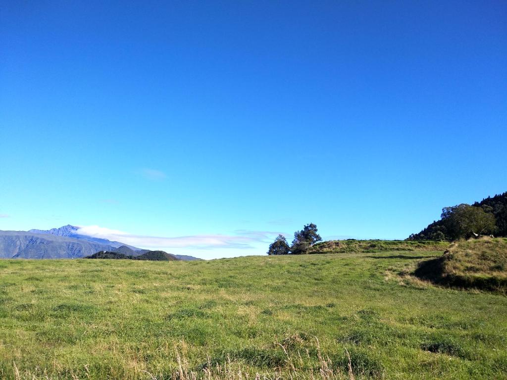 um campo de relva verde com montanhas ao fundo em Changement d'air près du volcan em Le Tampon