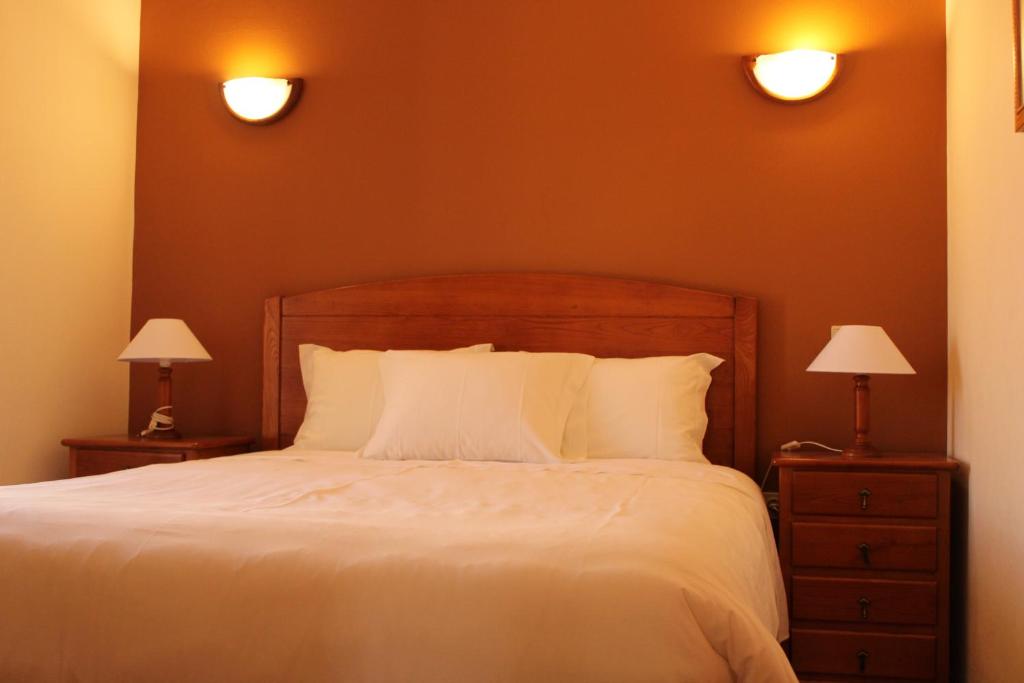 een slaapkamer met een bed met 2 nachtkastjes en 2 lampen bij Canto do Rossio in Vidigueira