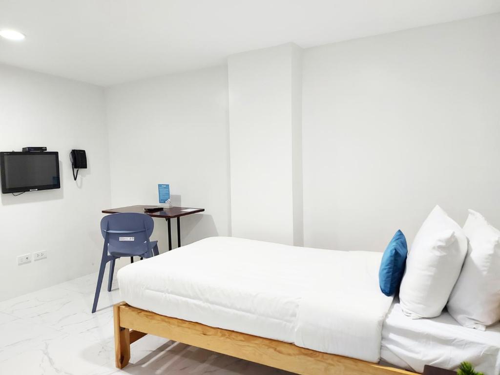 a white bedroom with a bed and a desk at airobedz MAKATI - A Value Hotel in Manila