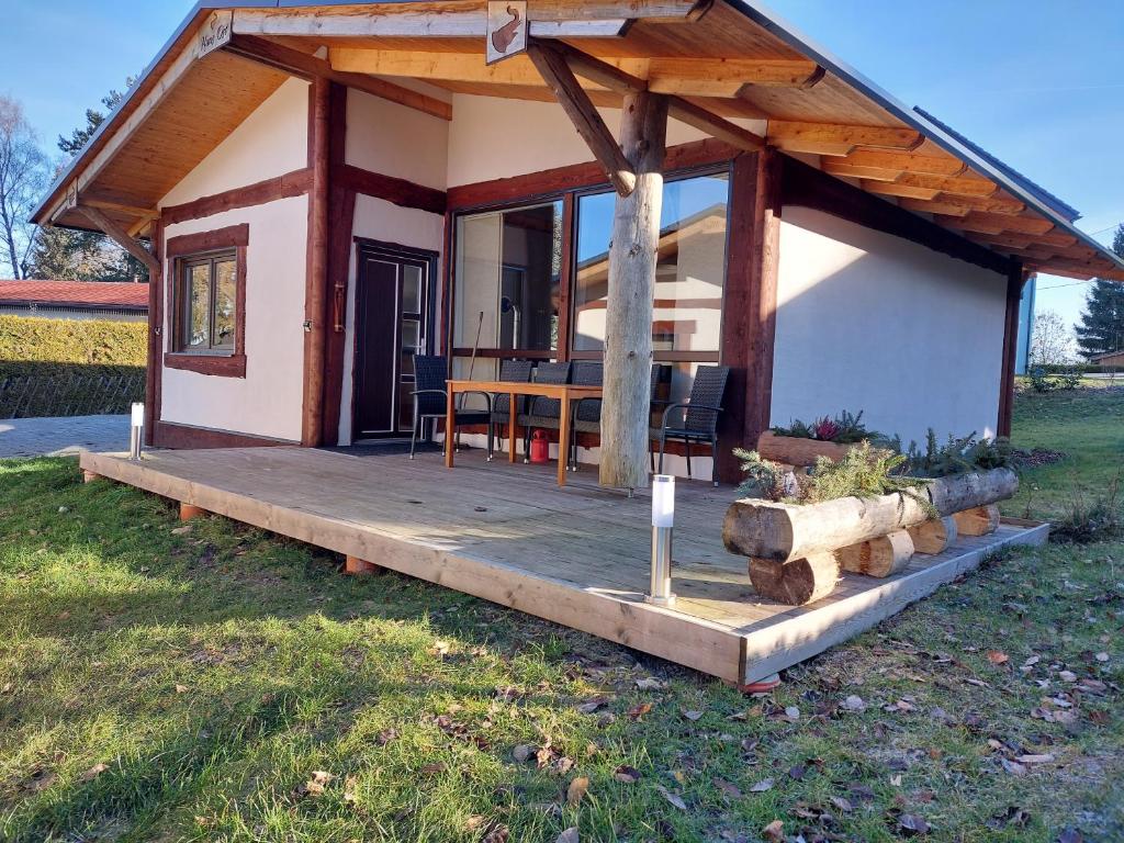 a small cabin with a wooden deck and a table at elephants Ferienhaus Haus Ost in Jahnsdorf