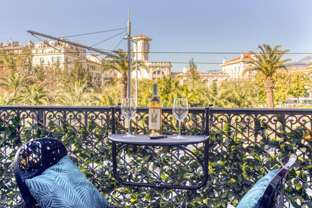 une table avec une bouteille et des verres sur un balcon dans l'établissement LE JEAN JAURES - REFAIT A NEUF, LUMINEUX, LONG BALCON, JOLIE VUE, WIFI, Cœur VIEUX-NICE, à Nice