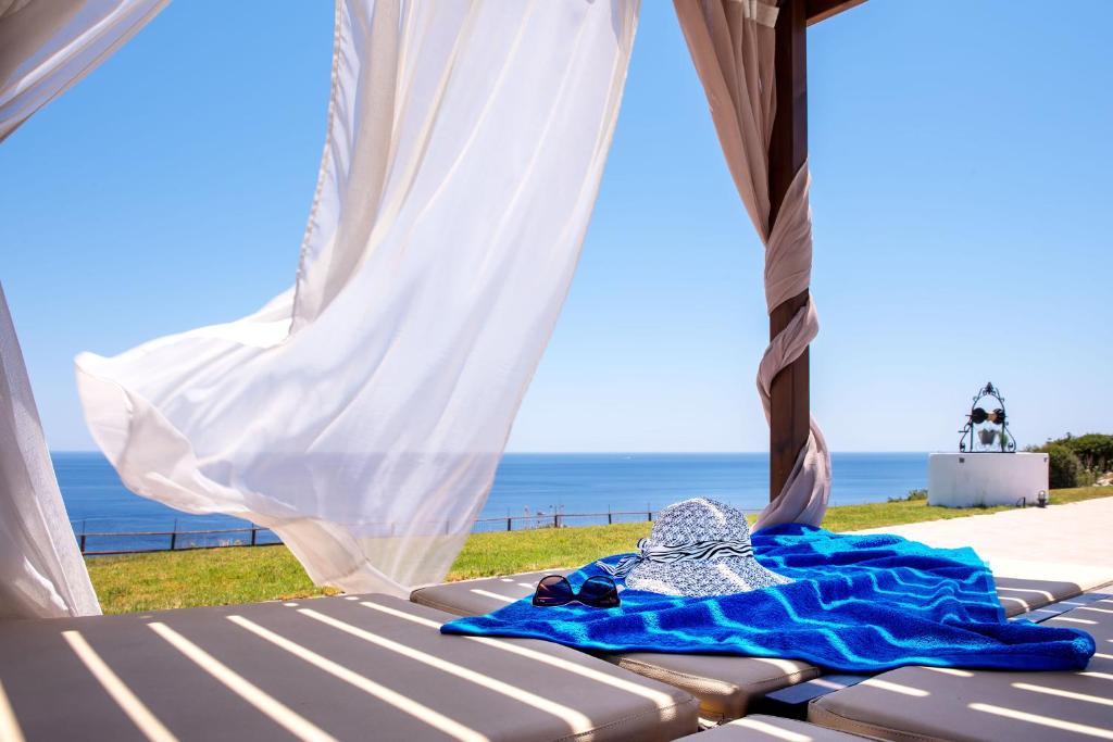 a bed with a blue blanket and a view of the ocean at Villa Pasithea in Faliraki