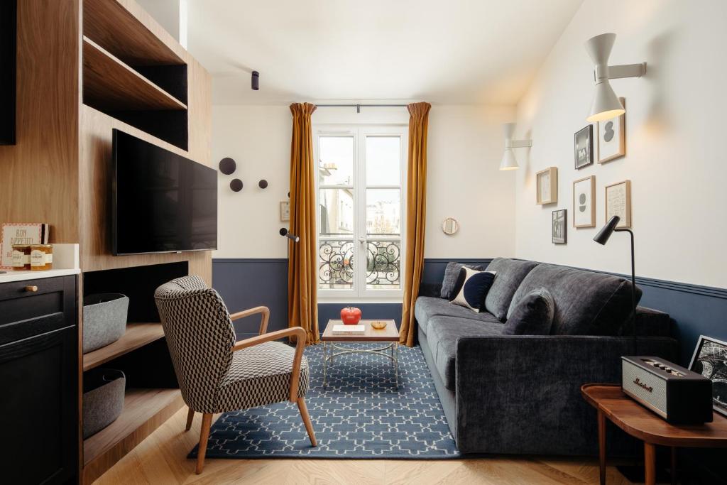 Una sala de estar con un sofá y un televisor. en My Maison In Paris Montmartre, en París