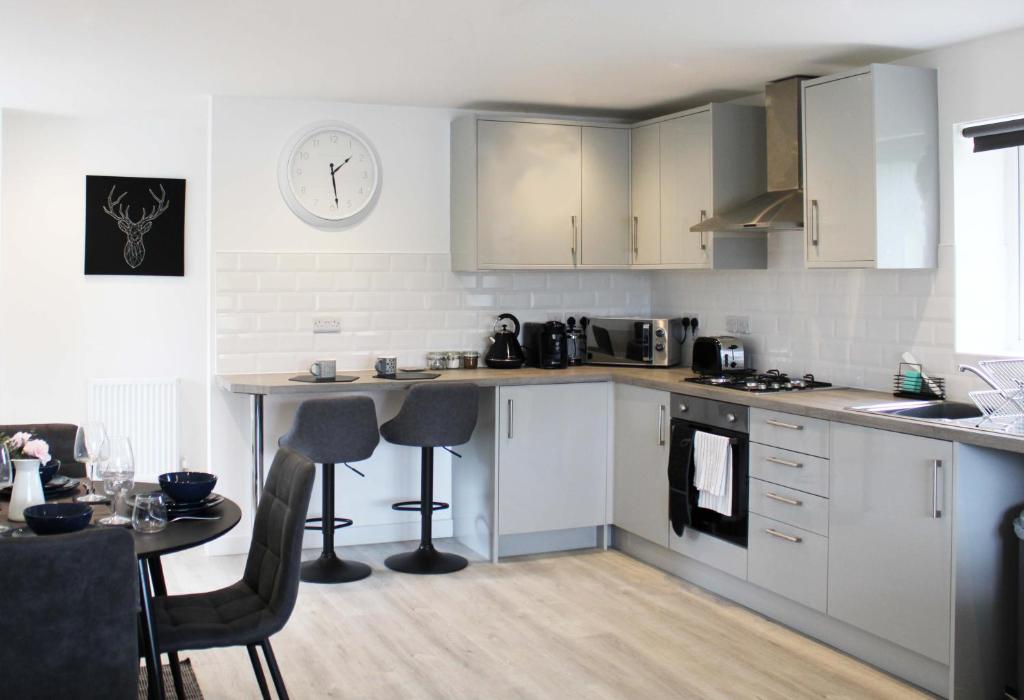 cocina con armarios blancos, mesa y reloj en Abingdon - Private Flat with Parking 09, en Abingdon