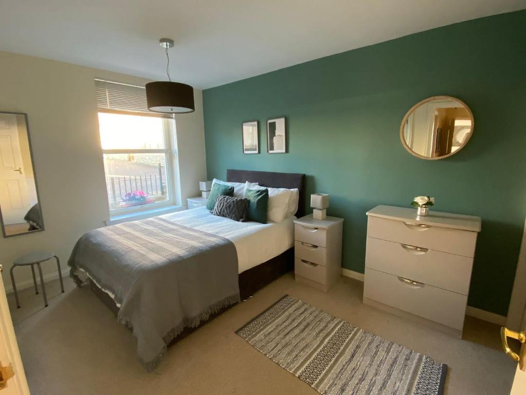 um quarto com uma cama, um espelho e uma janela em Maltings Apartment - Spacious 2 Bed Ground Floor Apartment em Kirkcaldy