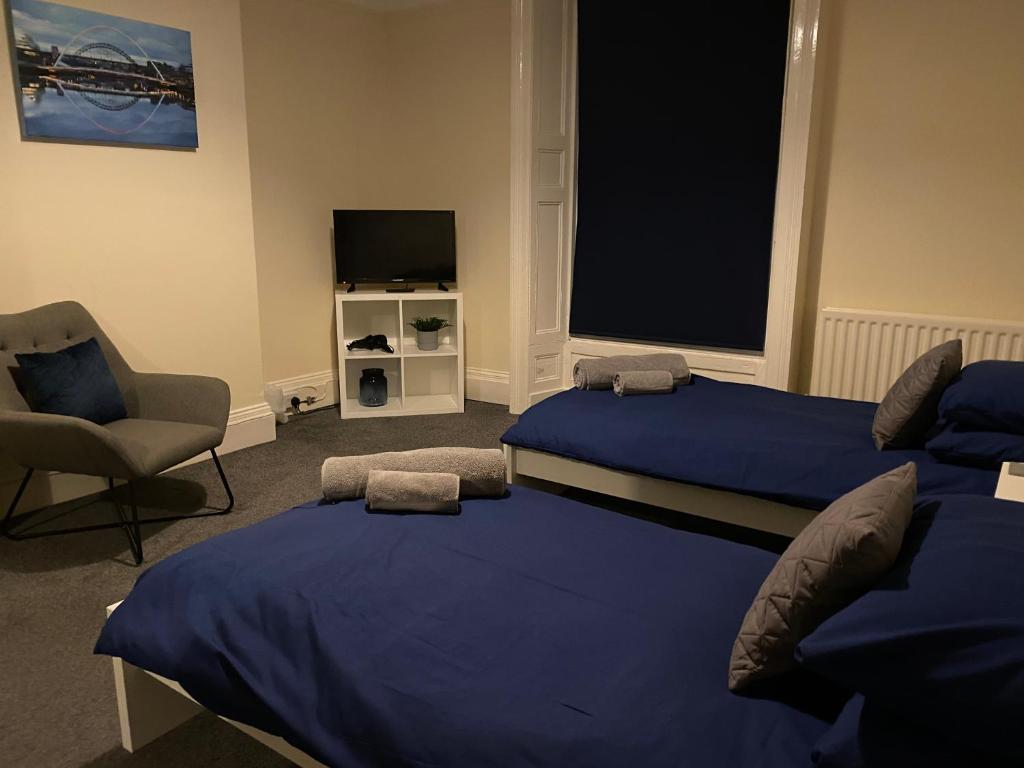 1 dormitorio con 2 camas, silla y TV en Town centre stay Northumberland FREE WIFI AND CLOSE TO BEACH en Blyth