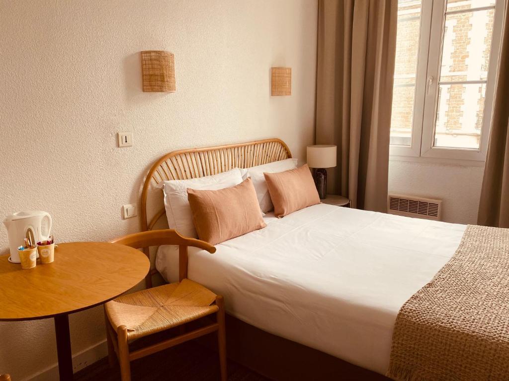 a hotel room with a bed and a table and a window at Hôtel Le Britannic - centre gare- in Saint Malo