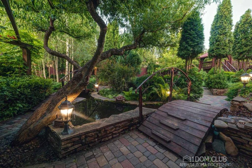 einen Garten mit einer Holzbank und einem Teich in der Unterkunft Дом на берегу in Protsev