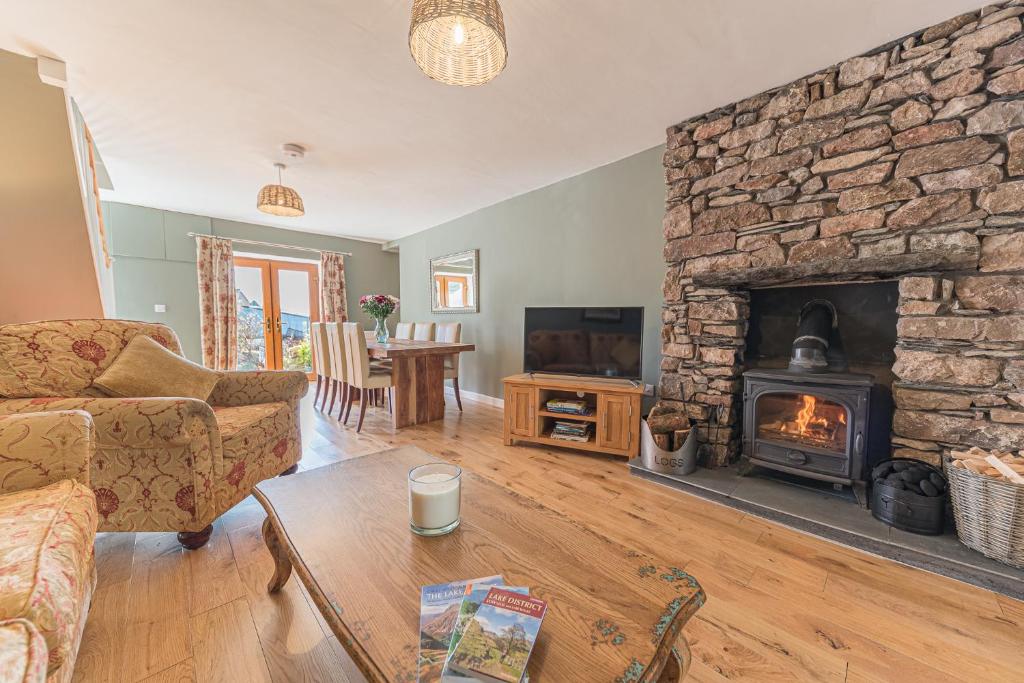 a living room with a stone fireplace and a table at The Black Dog Cottage in Dalton in Furness