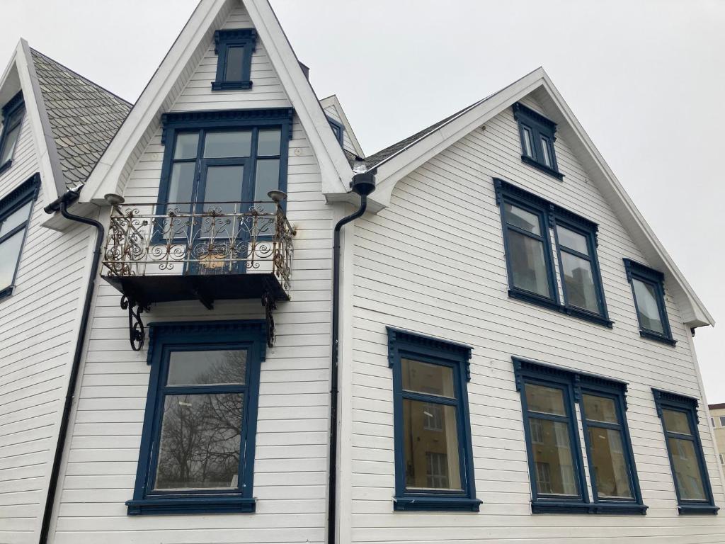 a white house with black windows and a balcony at Downtown Historical House with Renovated apartments in Ålesund