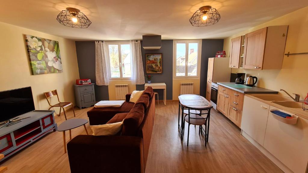 ein Wohnzimmer mit Sofa und eine Küche in der Unterkunft Le Studio Bis - Appartement meublé tout confort Centre Ville in Pont-Sainte-Maxence