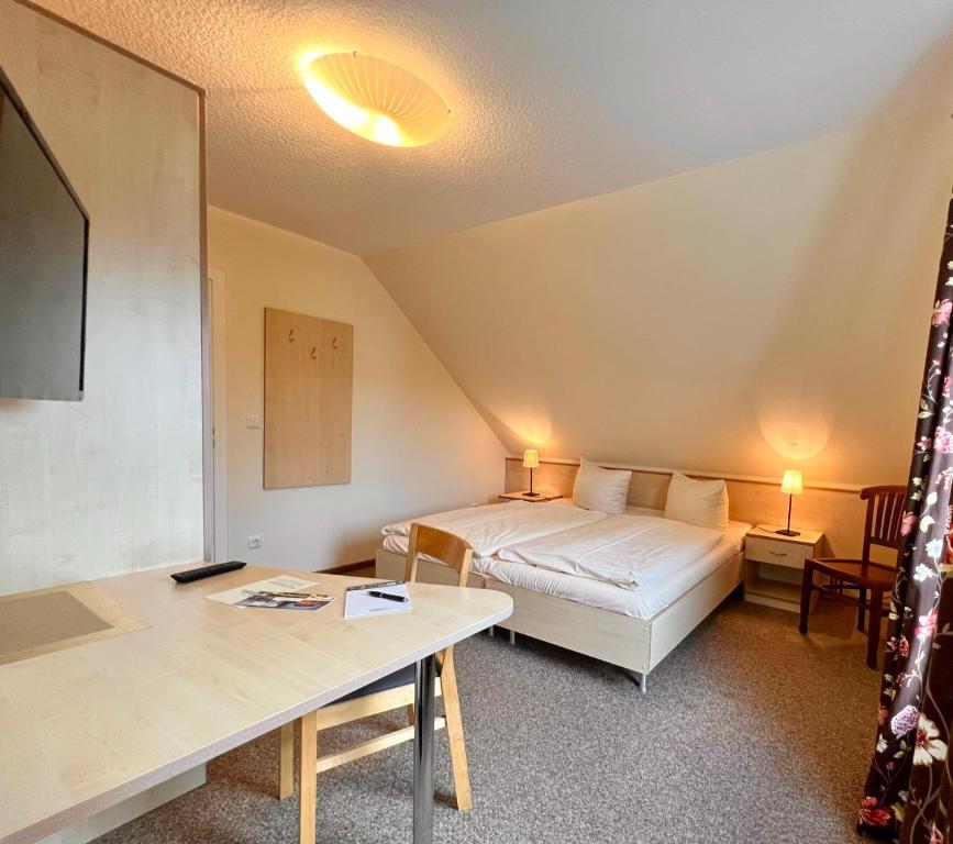 um pequeno quarto com uma cama e uma mesa em Gästehaus Südheide em Hambühren