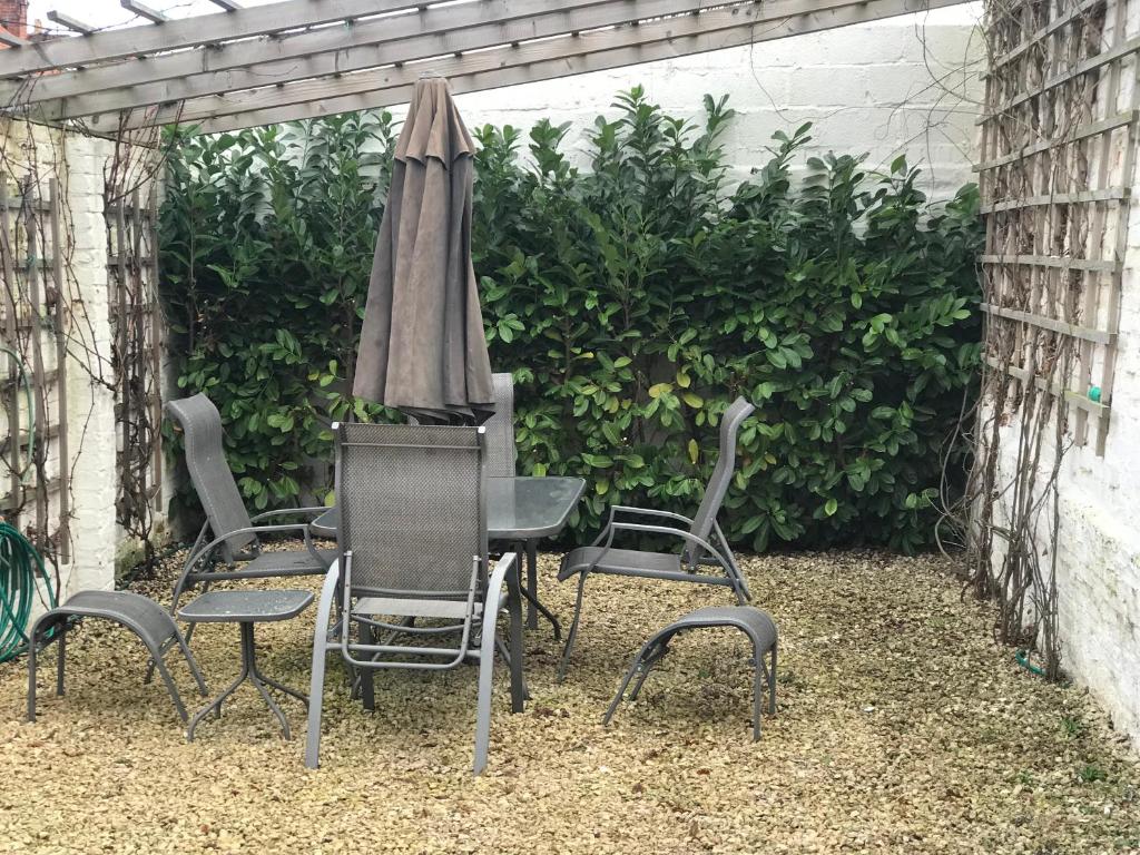 un groupe de chaises, une table et un parasol dans l'établissement Cozy lodge with private garden and bbq, à Barton-upon-Humber