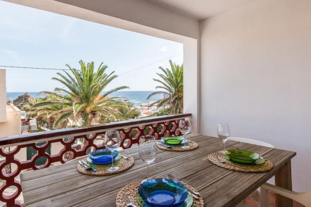 a table with wine glasses and a view of the ocean at Apartamento Sa Mesquida 11 in Cala Llonga