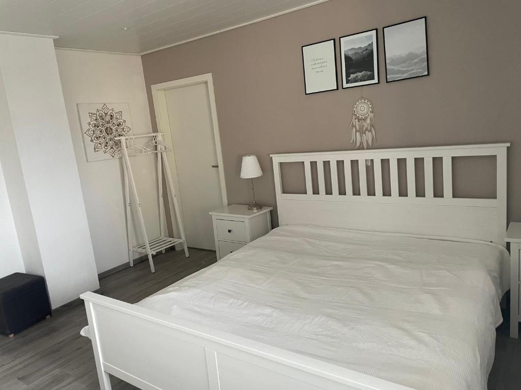 a white bedroom with a white bed and pictures on the wall at Diamant Apartment in Gattendorf
