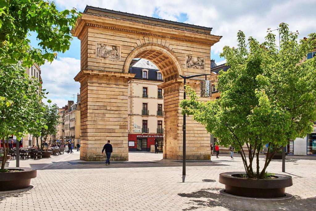 un bâtiment avec une arche au milieu d'une rue dans l'établissement Logis Hotel Darcy Dijon Centre, à Dijon