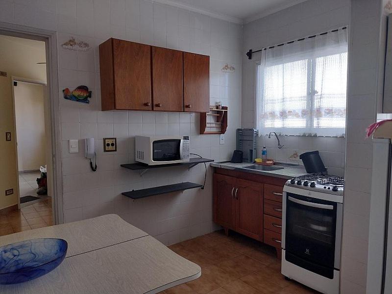 a kitchen with a stove and a microwave at Apto Aconchegante Praia Grande in Praia Grande